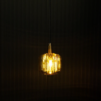 Amber glass pendant light glowing softly against a black backdrop showcases its elegant design and warm lighting effect.
