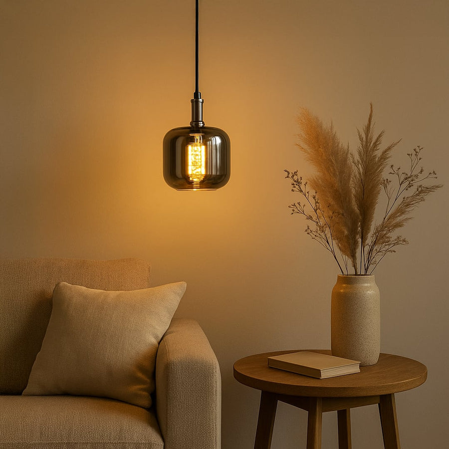 Glass pendant light in amber hue illuminating a cozy living room with a sofa and vase creating a warm and inviting ambiance.