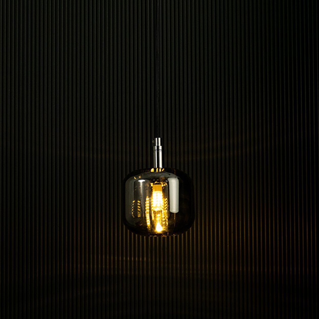 Amber glass pendant light glowing against a dark backdrop showcasing its elegant design and warm lighting effect.