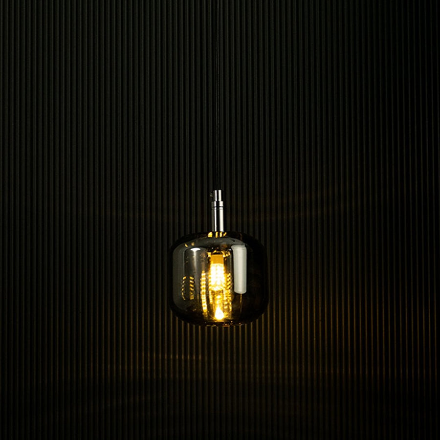 Amber glass pendant light glowing against a dark backdrop showcasing its elegant design and warm lighting effect.