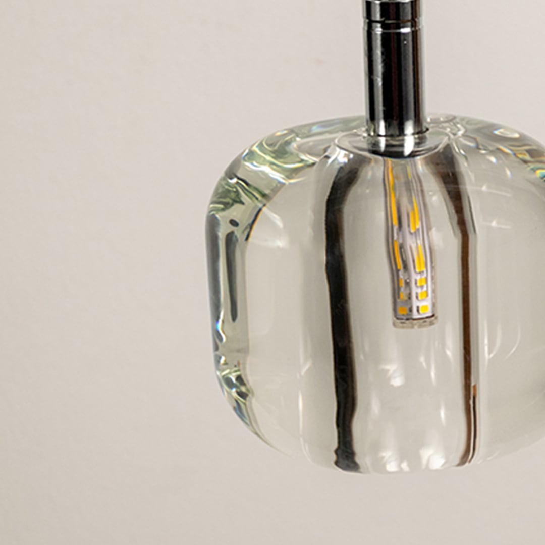 Close up of an amber glass pendant light highlighting its sleek design and the warm glow from the exposed bulb.