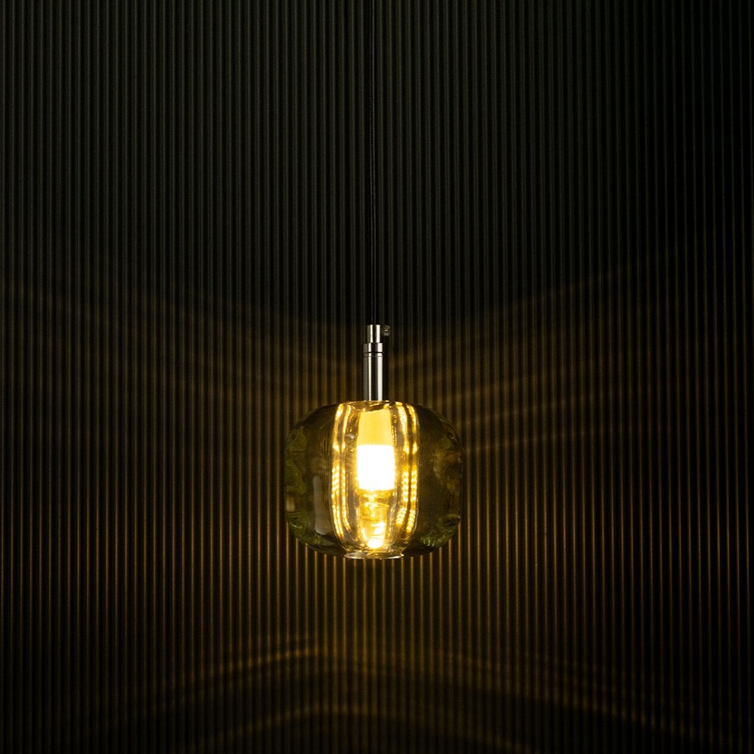 Amber pendant light shining softly against a dark backdrop emphasizes its sleek design and creates a warm and inviting effect.
