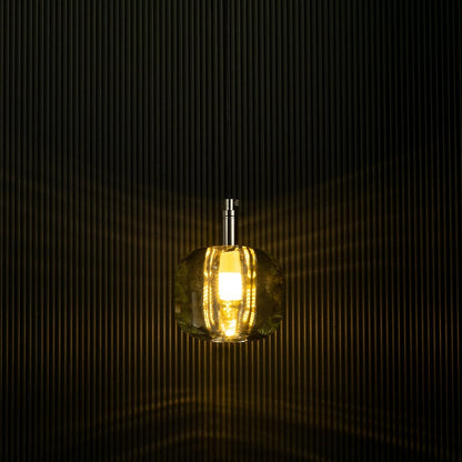 Amber pendant light shining softly against a dark backdrop emphasizes its sleek design and creates a warm and inviting effect.