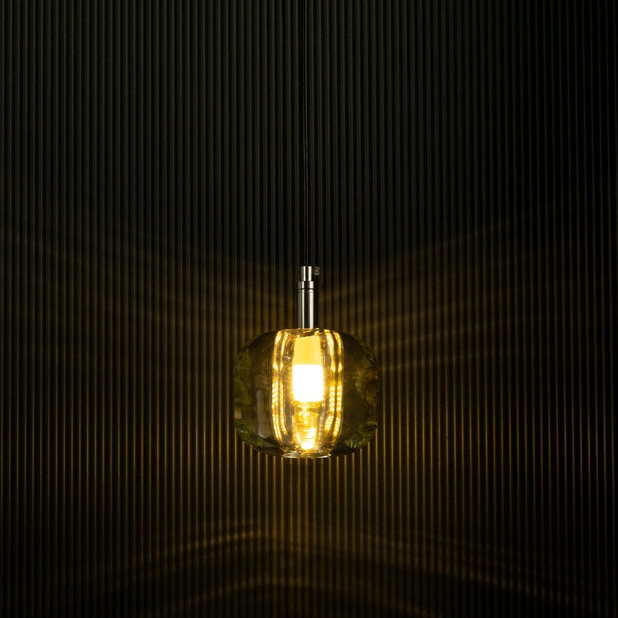 Amber pendant light shining softly against a dark backdrop emphasizes its sleek design and creates a warm and inviting effect.