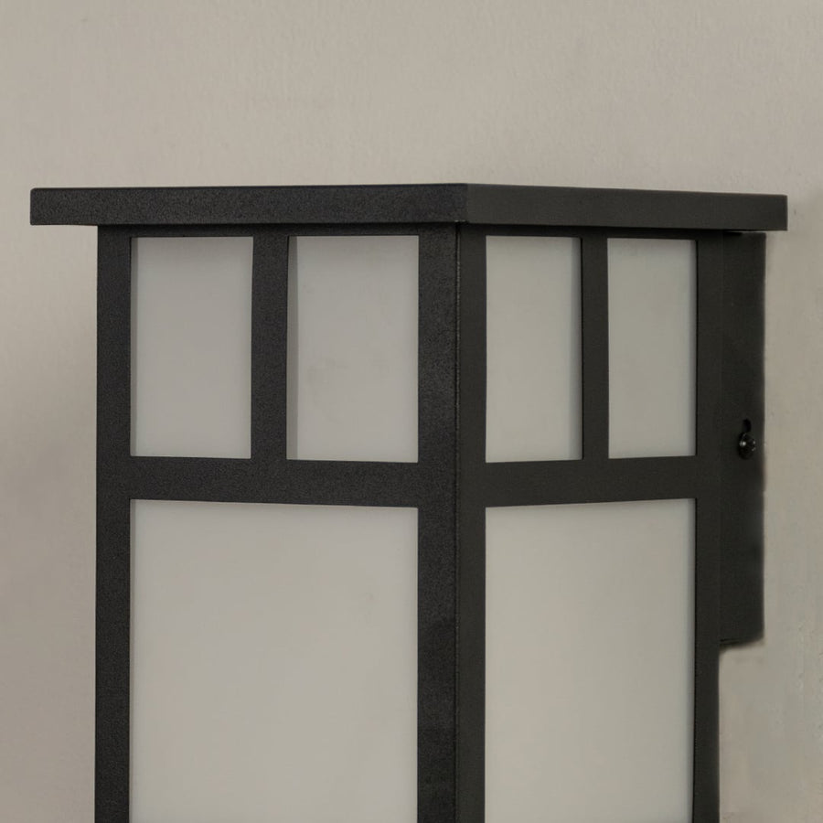 Closeup view of the black outdoor wall light highlighting its structured frame and frosted glass panels.