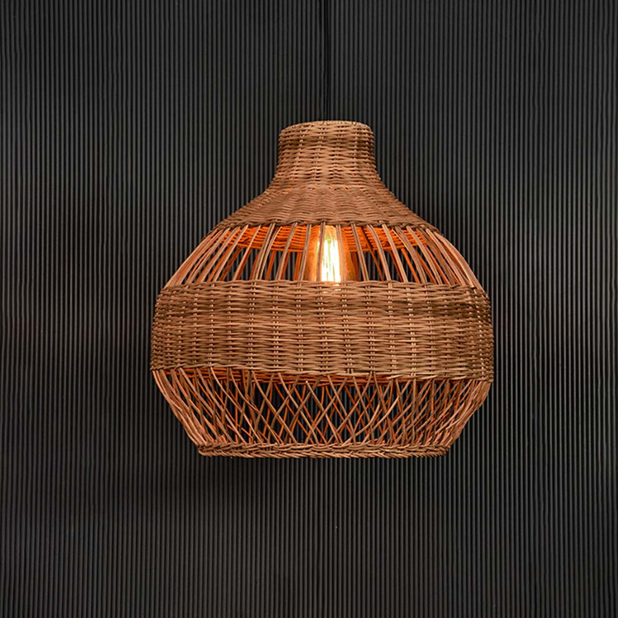 Natural rattan pendant light glowing beautifully on black background highlighting texture and woven detail.