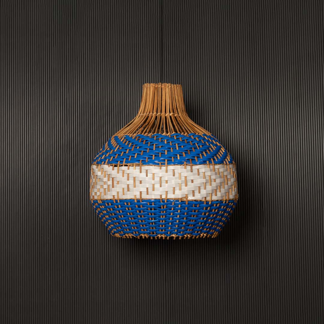 Blue and natural rattan pendant light on black background highlighting its woven texture and elegant handcrafted design.
