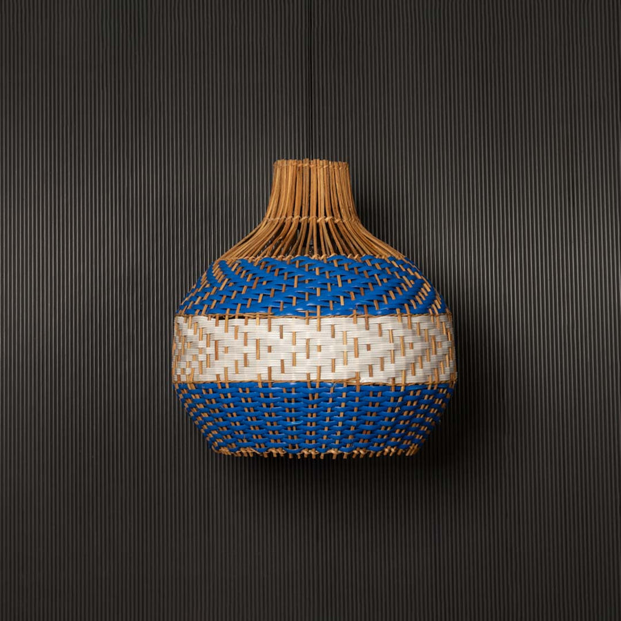 Blue and natural rattan pendant light on black background highlighting its woven texture and elegant handcrafted design.