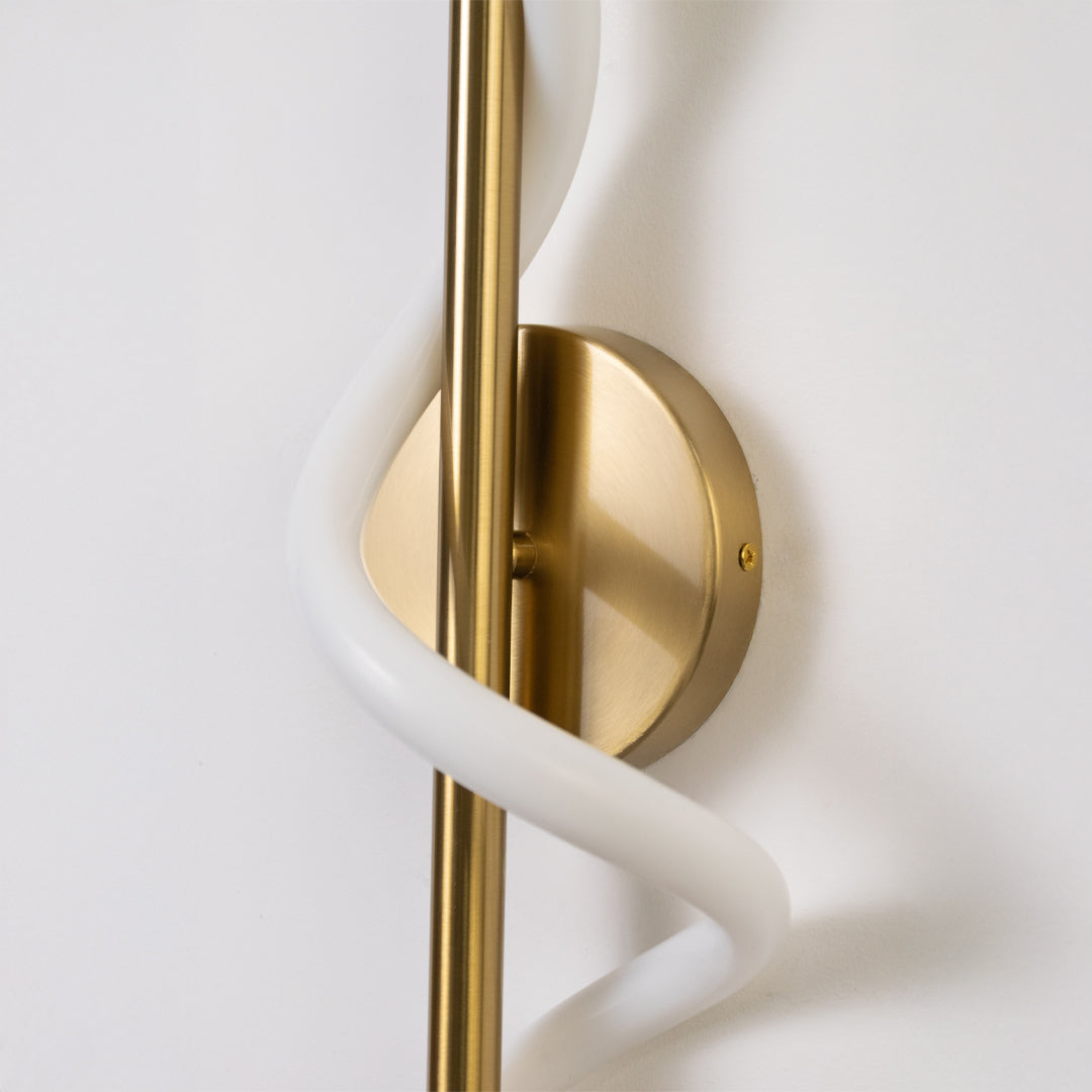 Closeup wall light in gold metal finish with sculpted white tube design for bedroom or living decor lighting white background.