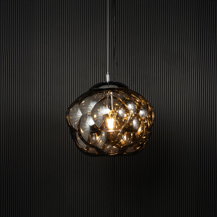 Smokey glass bubble pendant light glowing on black background with artistic round shade for stylish home lighting.