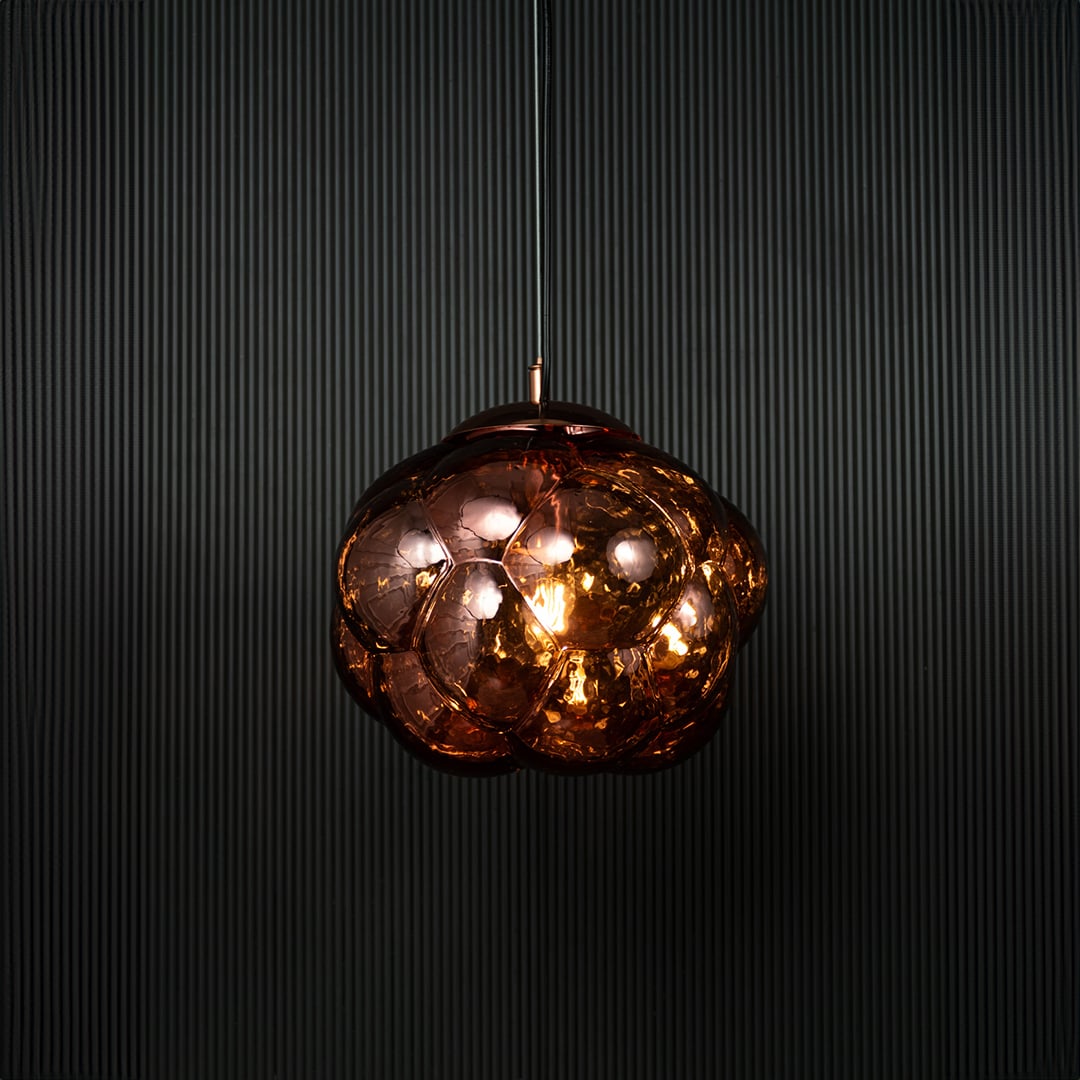 Brown glass bubble pendant light glowing on black background with reflective surface and artistic round design.