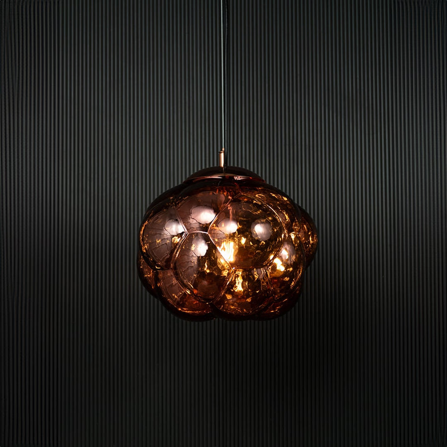 Brown glass bubble pendant light glowing on black background with reflective surface and artistic round design.