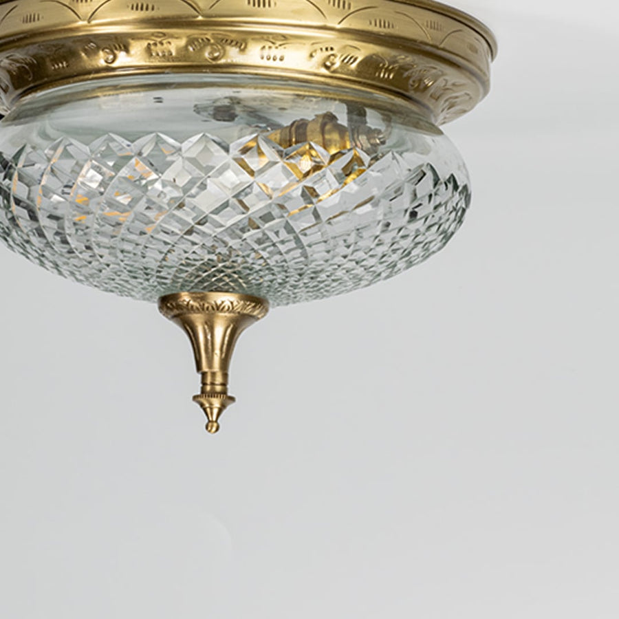 Closeup of antique brass and cut crystal flush mount ceiling light for luxury traditional interior decor styling spaces.