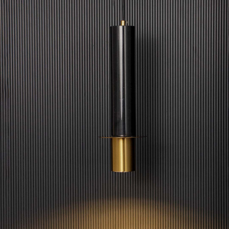 Elegant cylindrical black and gold pendant ceiling light glowing beautifully against dark black background for modern decor.