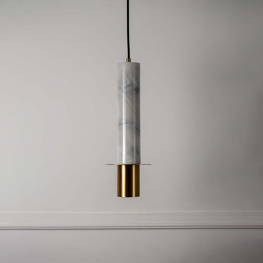 Modern pendant light with white marble cylindrical body and brass gold base shown turned off highlighting luxury design.