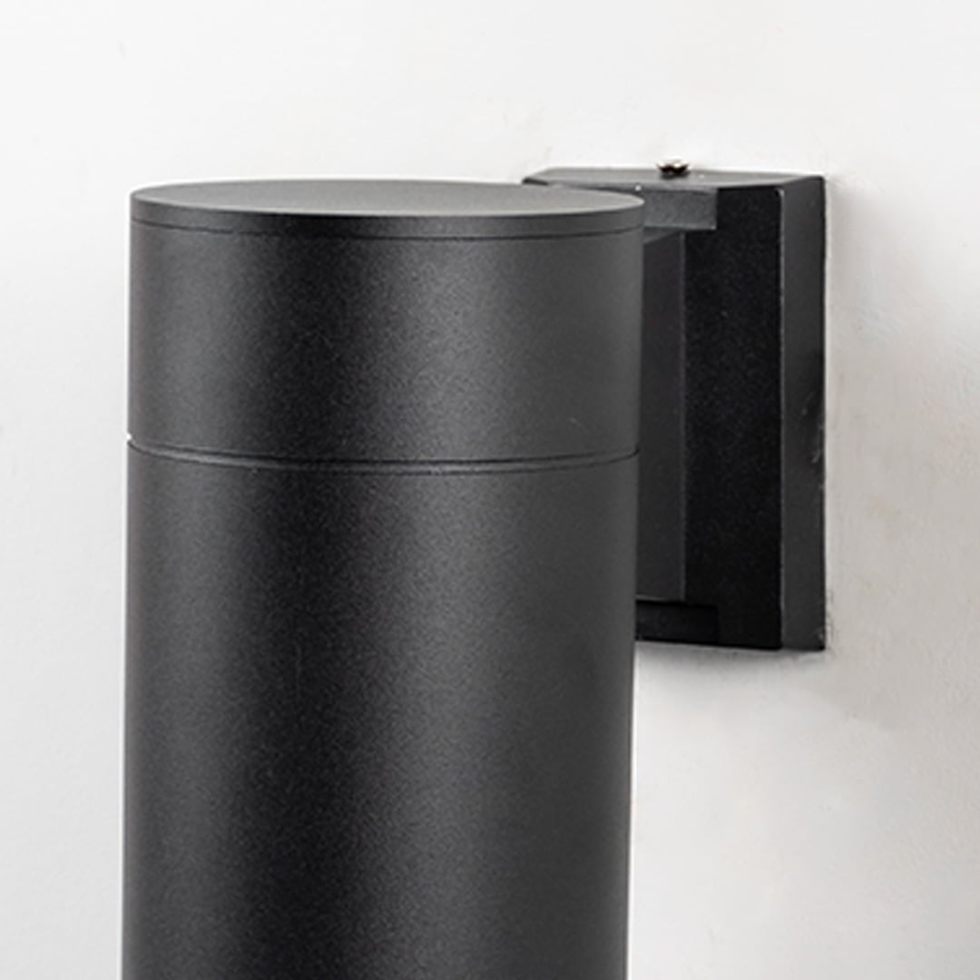Closeup of black metal cylindrical outdoor wall light showing smooth matte finish and sleek modern design for exterior use.