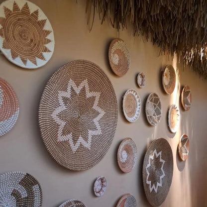 A set of woven jute wall plates in beige and white sun patterns displayed together creating a textured boho feature wall with warm natural decor styling.