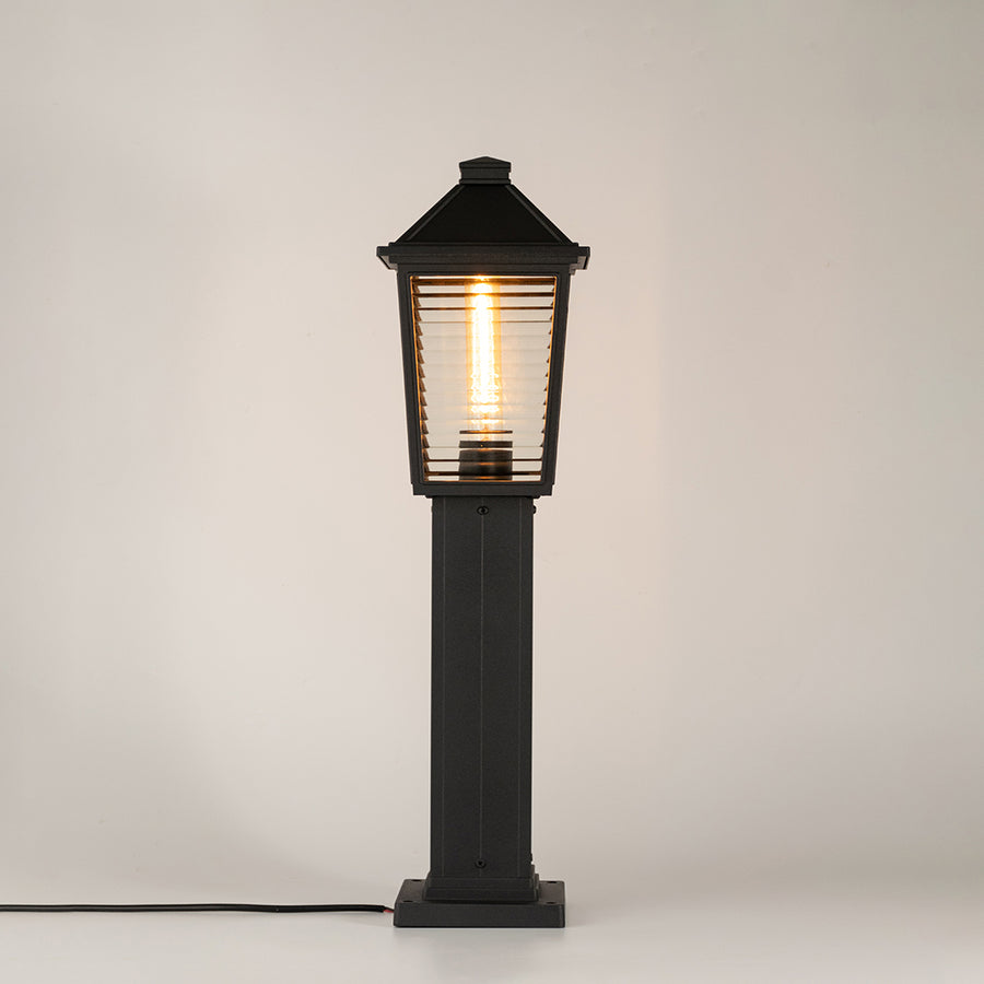 Modern black outdoor bollard light with ribbed glowing panels for stylish exterior decor use.
