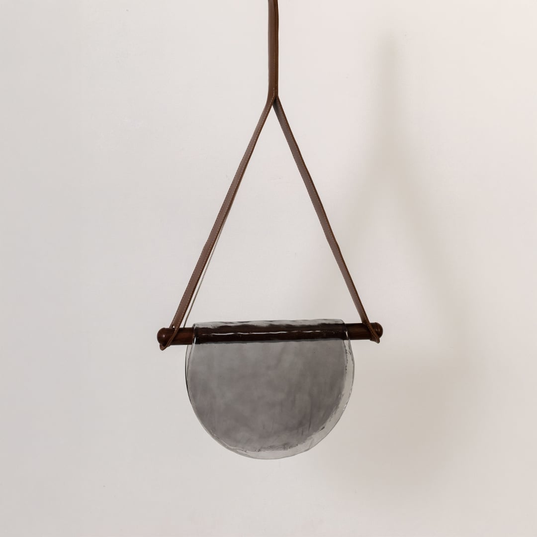 Pendant light with grey half-moon textured glass shade shown turned off against a white background highlighting its elegant design.