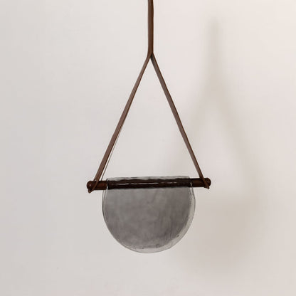 Pendant light with grey half-moon textured glass shade shown turned off against a white background highlighting its elegant design.