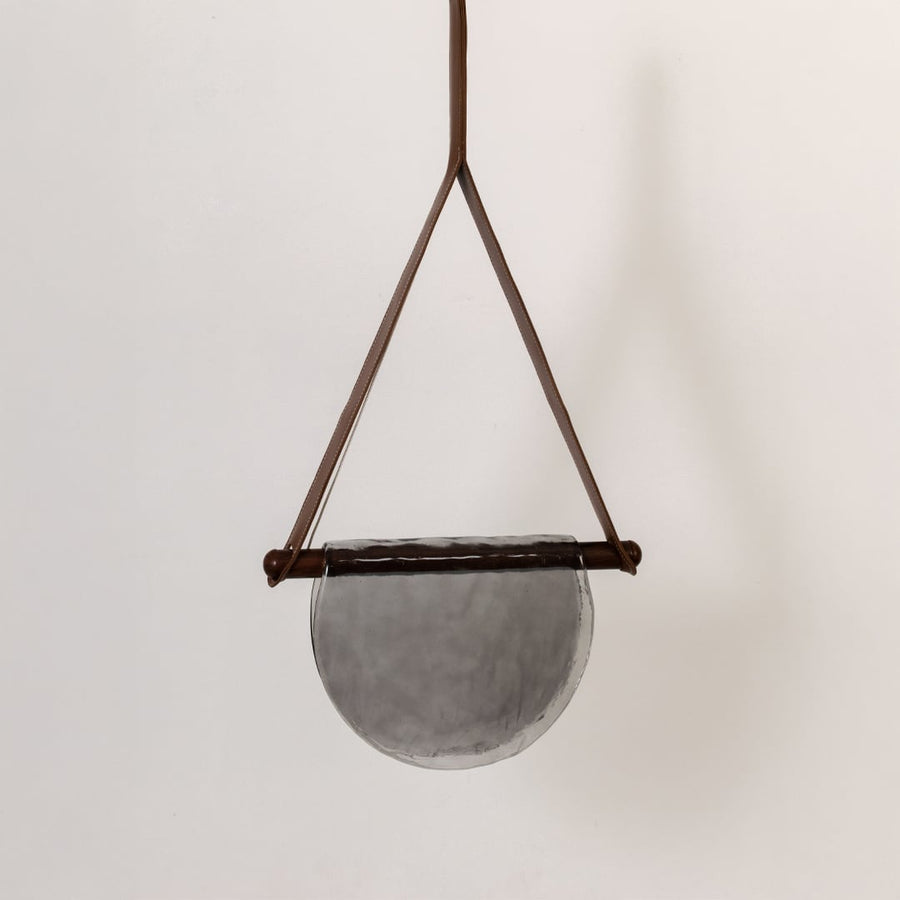 Pendant light with grey half-moon textured glass shade shown turned off against a white background highlighting its elegant design.