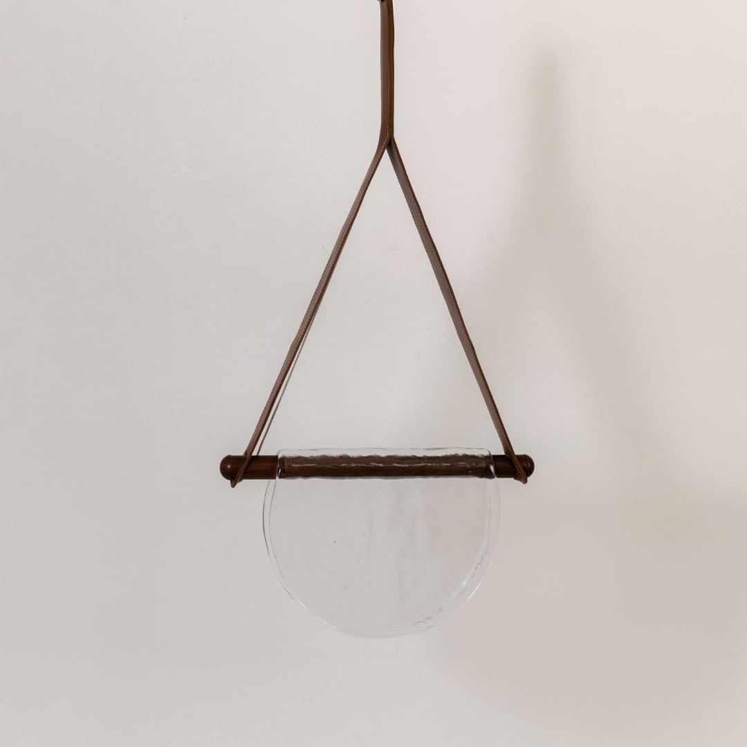 Pendant light with clear half-moon textured glass shade shown turned off against a white background highlighting its simple elegant design.