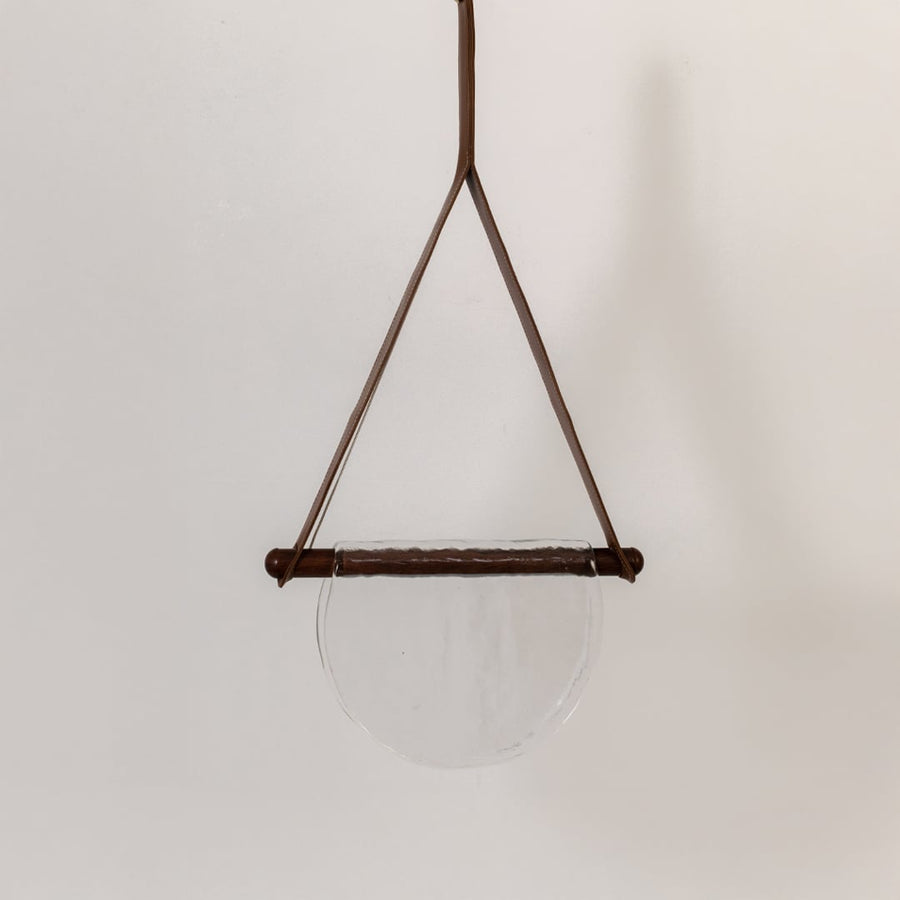 Pendant light with clear half-moon textured glass shade shown turned off against a white background highlighting its simple elegant design.