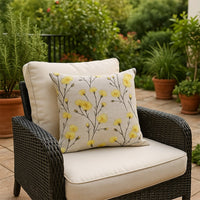 White cotton cushion cover with yellow botanical embroidery placed on an outdoor chair bringing a fresh natural style to patio décor with a soft breathable skin friendly fabric.