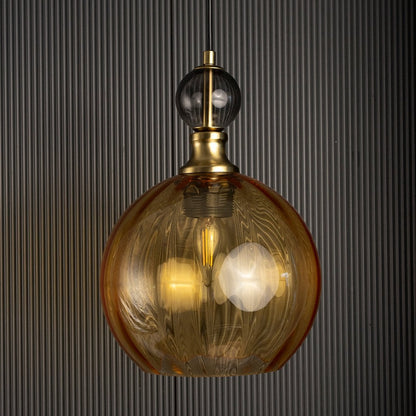 Amber glass pendant light turned off against a dark background highlighting its rich texture and golden tones.