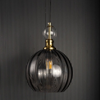 Smoky glass pendant lamp turned off against black background with gold metal holder and clear glass top accent designed for modern interiors.