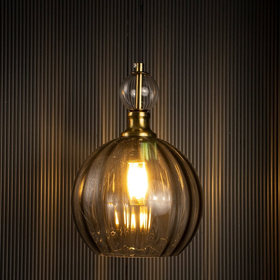 Smoky glass pendant light glowing against a dark background showcasing its ribbed glass texture and golden hue.