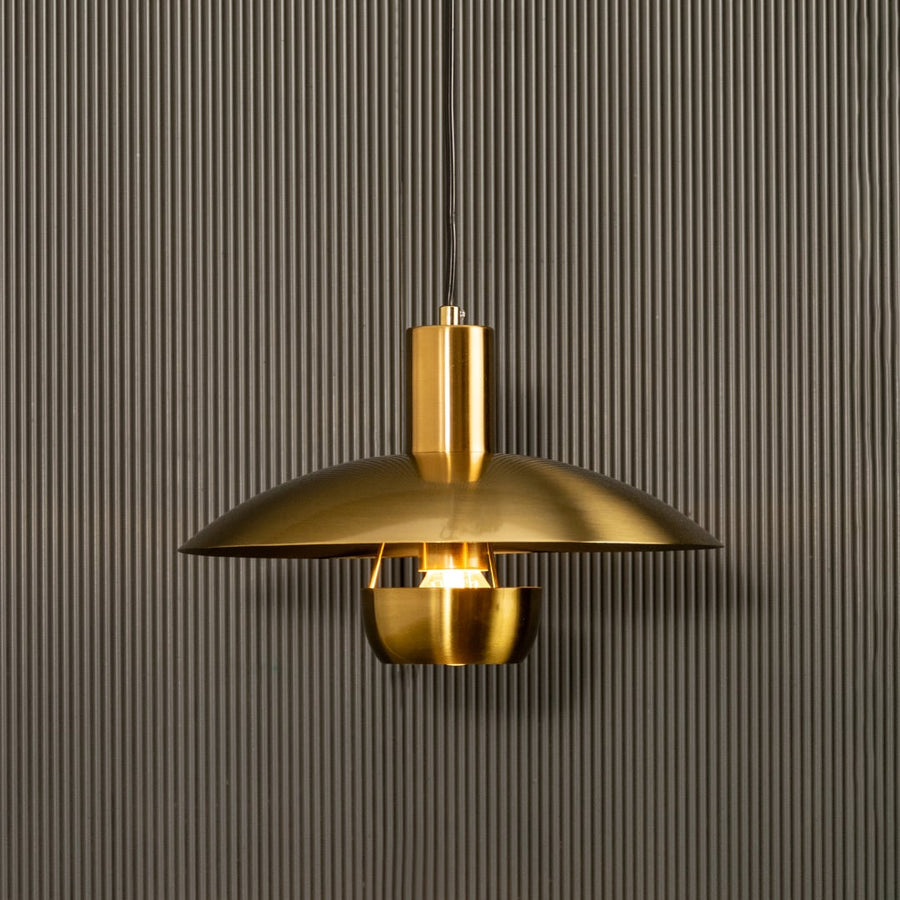 Golden metal pendant light shining warmly on dark background accentuating its smooth curves and contemporary luxe appeal.