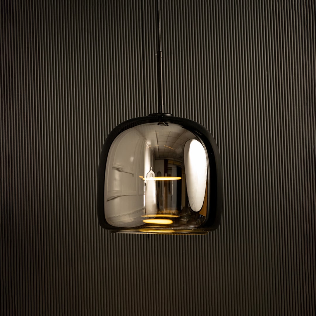 Metallic pendant light with a rounded reflective shade glowing warmly and adding a sleek modern lighting highlight that enhances the interior style.