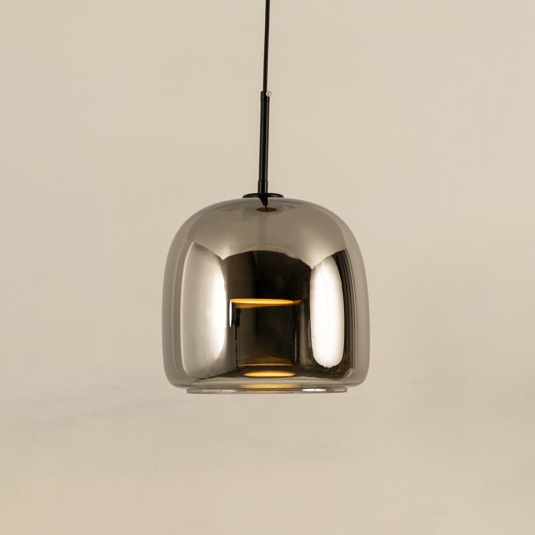 Metallic pendant light with a smooth rounded reflective shade hanging elegantly and producing a warm bright glow that adds a sleek contemporary accent to the room.