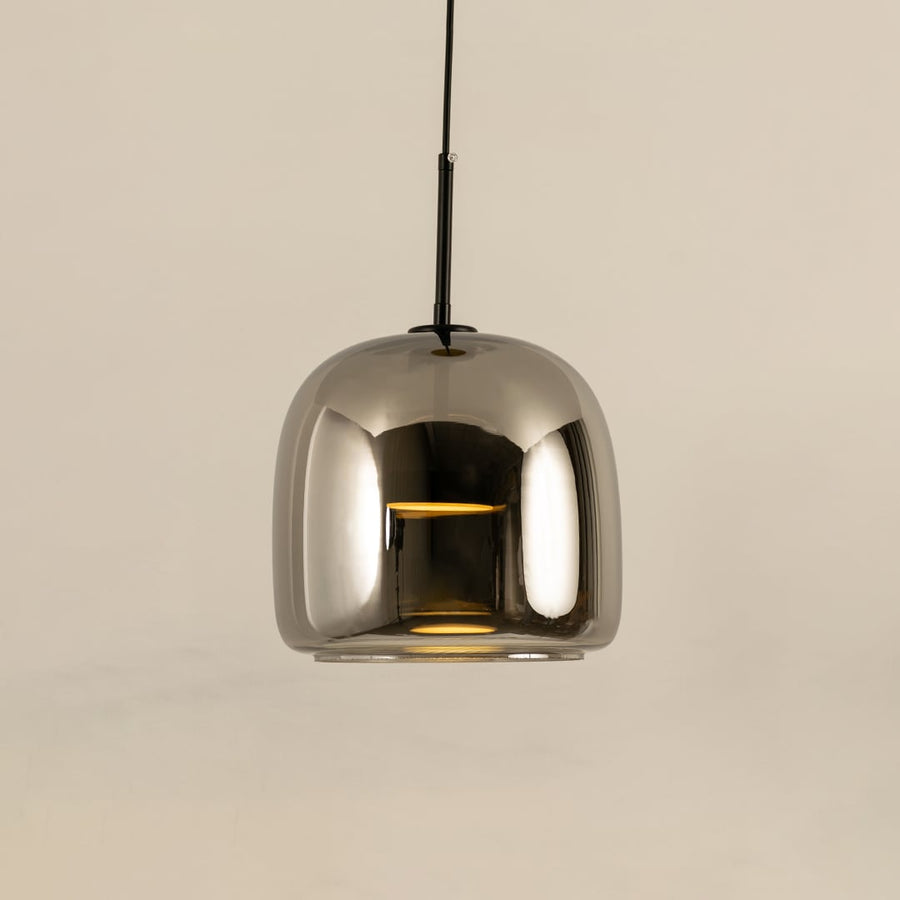 Metallic pendant light with a smooth rounded reflective shade hanging elegantly and producing a warm bright glow that adds a sleek contemporary accent to the room.