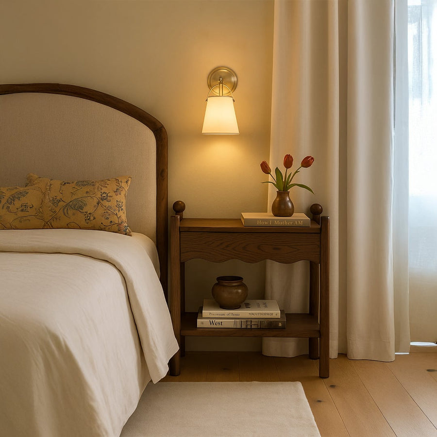 Gold metal wall light with cone shaped white fabric shade adding soft warm lighting to a contemporary room setting ideal for home interiors.