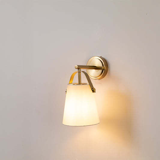 Modern wall light in gold metal finish with fabric shade for bedroom or living room decor lighting white background.