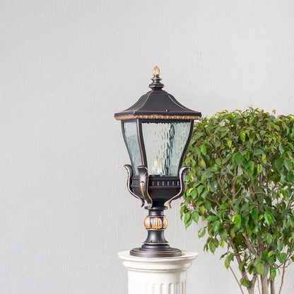 Stylish black and gold outdoor pillar light with clear glass shade displayed on decorative column shown in switched off mode.