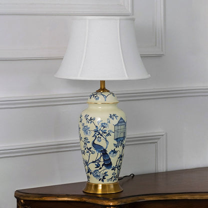 Blue floral ceramic lamp with bird motifs on ivory base displayed turned off against a clean white background.