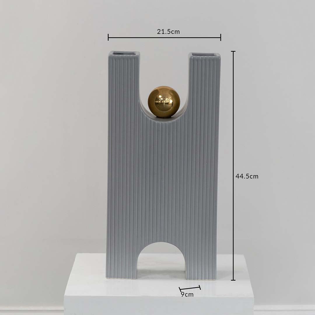 A grey sculptural decor piece with gold sphere displayed with measurements showing 21.5 cm width 44.5 cm height and 9 cm depth for accurate size reference.