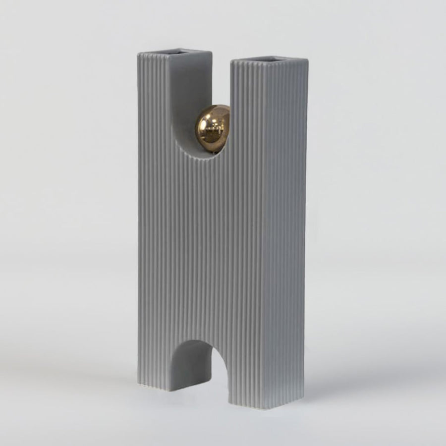 A contemporary grey geometric decor accent with a gold sphere captured on a clean white setup emphasising its tall structured and refined artistic form.