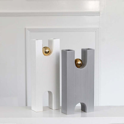 White ribbed modern sculpture with gold sphere grouped with decor pieces creating a refined contemporary display for interiors.