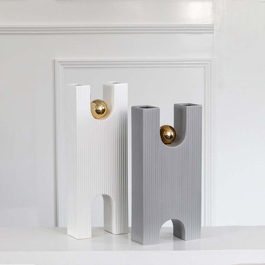 White ribbed modern sculpture with gold sphere grouped with decor pieces creating a refined contemporary display for interiors.