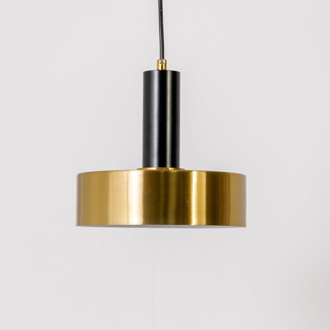 Gold and black metal pendant light on white background with light off highlighting its matte black stem and polished gold cylindrical shade.