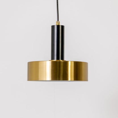 Gold and black metal pendant light on white background with light off highlighting its matte black stem and polished gold cylindrical shade.