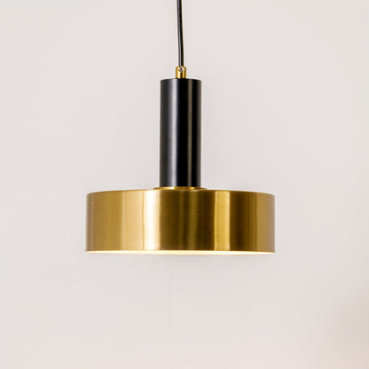 Gold and black metal pendant light on white background with light on displaying a warm downward glow and a sleek modern circular design.