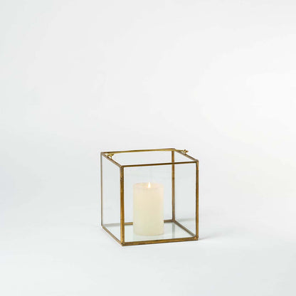 Minimal gold metal candle lantern with clear glass panels for elegant modern decor styling.