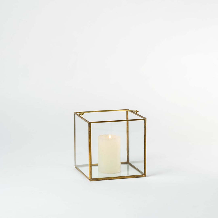 Minimal gold metal candle lantern with clear glass panels for elegant modern decor styling.