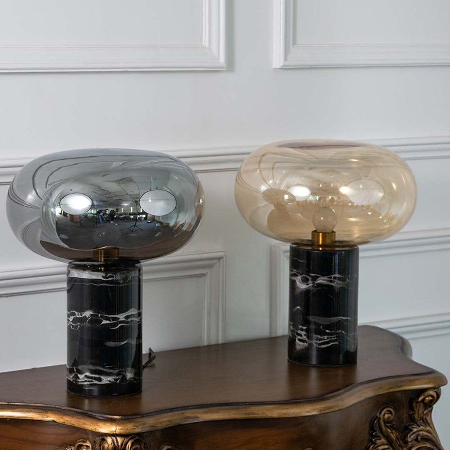Collection of contemporary smoked glass table lamps with black marble bases on white background showcasing timeless modern elegance.