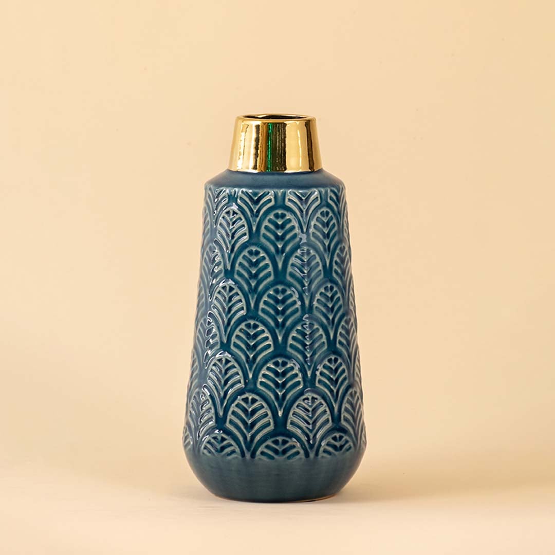 Closeup of blue ceramic vase highlighting the embossed leaf pattern glossy blue glaze and reflective gold neck perfect for adding a decorative touch to interiors.
